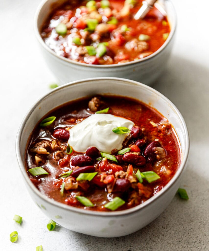 chili in a bowl topped with sour cream and green onions