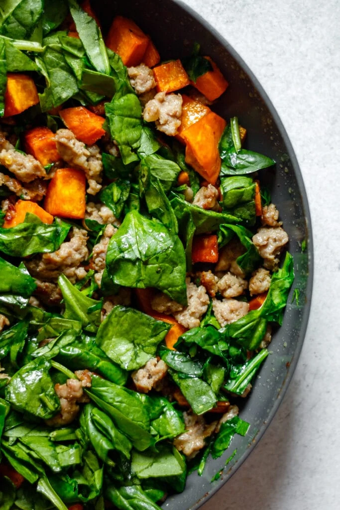 spinach, sausage, and sweet potatoes in a non-stick pan