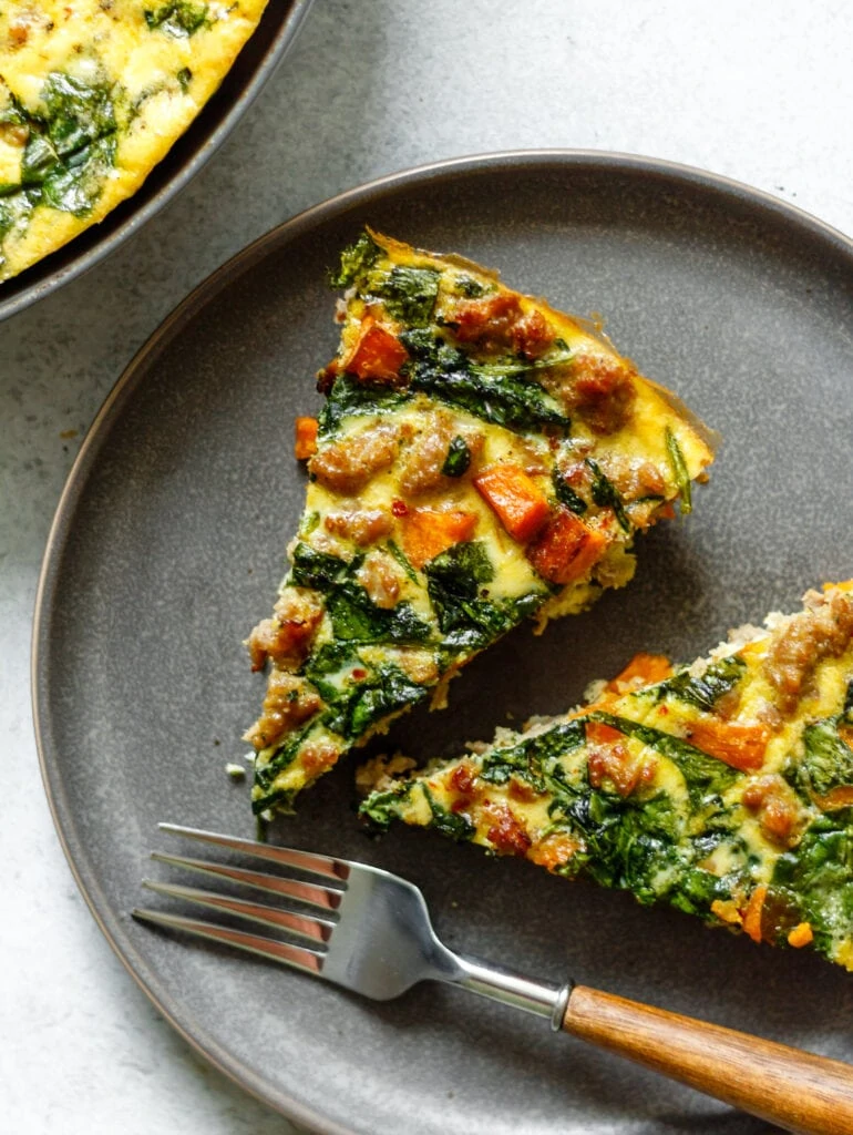 two slices of frittata on a grey plate with a fork