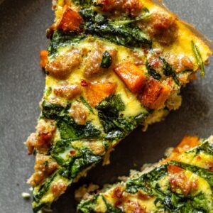 two slices of sweet potato and sausage frittata on a grey plate