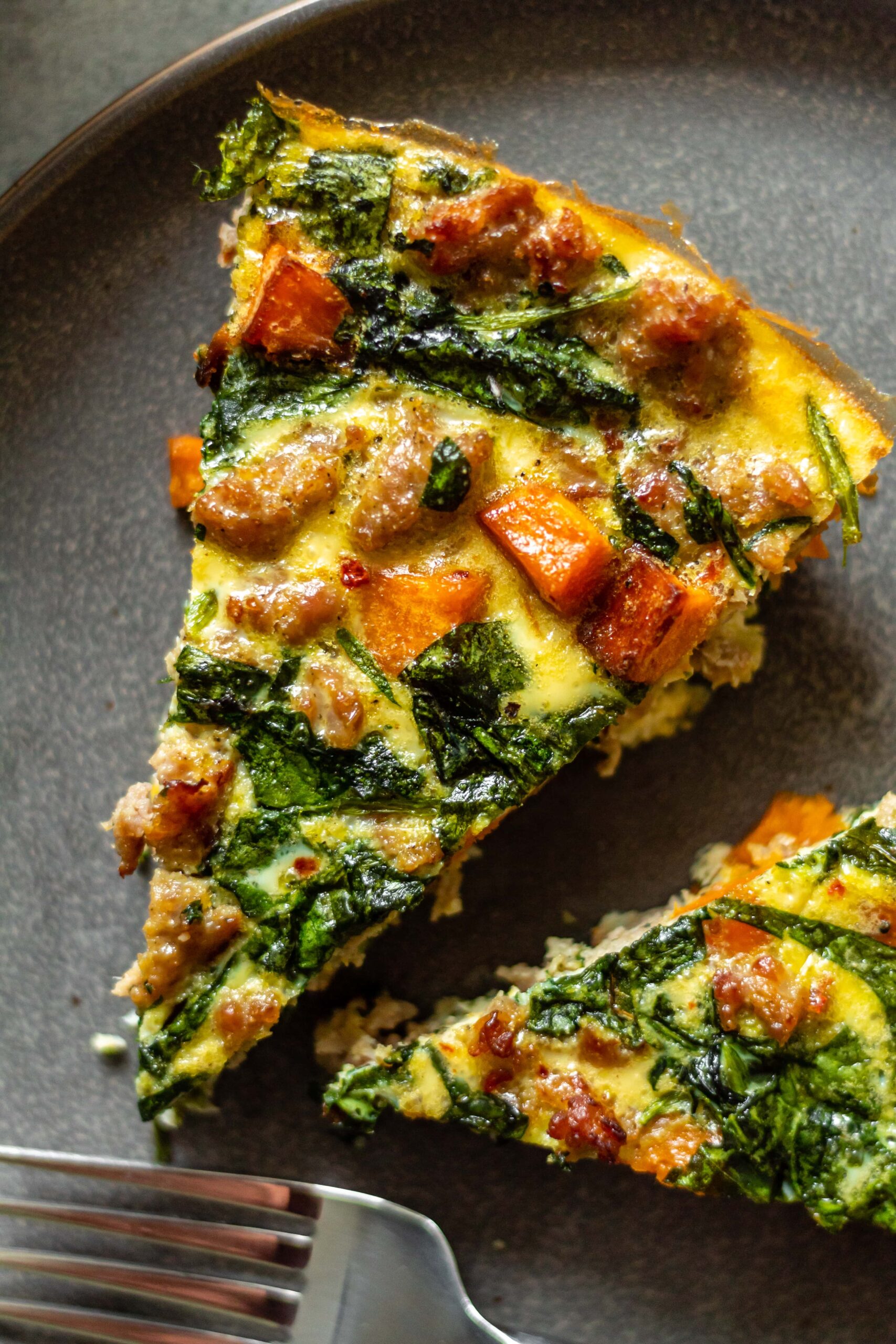 two slices of sweet potato and sausage frittata on a grey plate