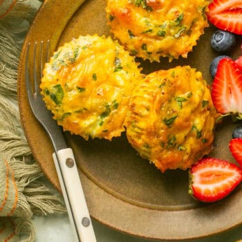 loaded egg bites on plate with fruit and fork