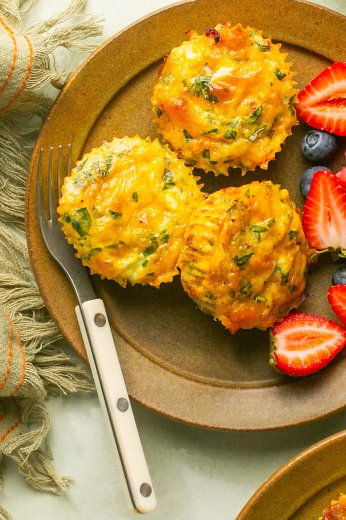 loaded egg bites on plate with fruit and fork