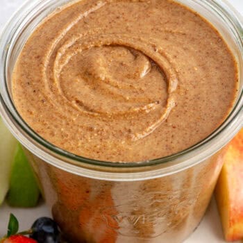 almond butter in glass jar on plate with fruit