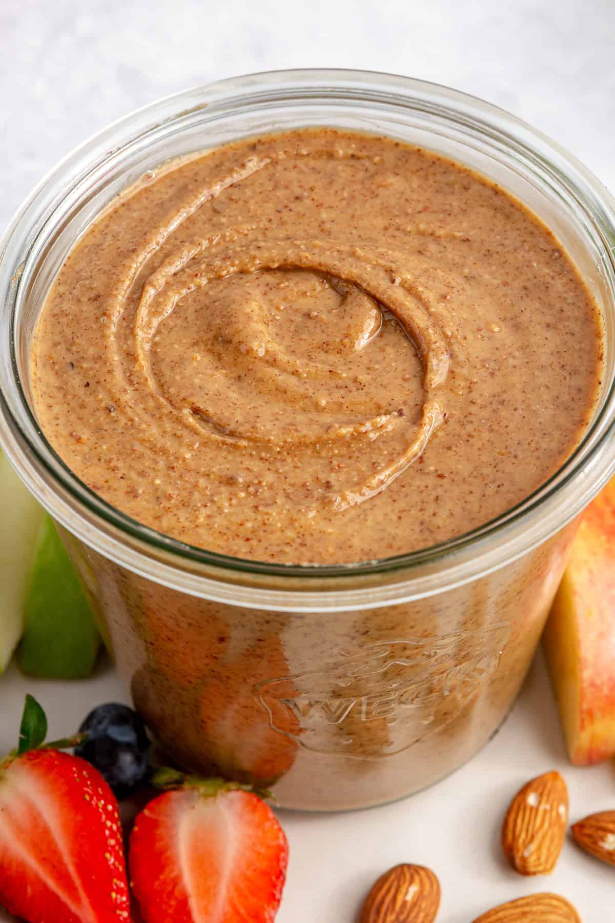 almond butter in glass jar on plate with fruit