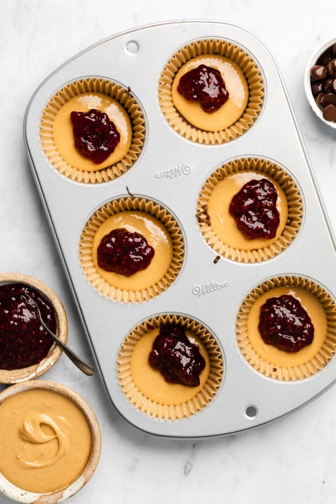 cashew butter and raspberry jam in muffin tin