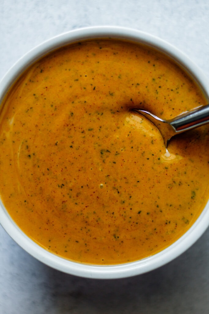 creamy peanut dressing in white ramekin with silver spoon