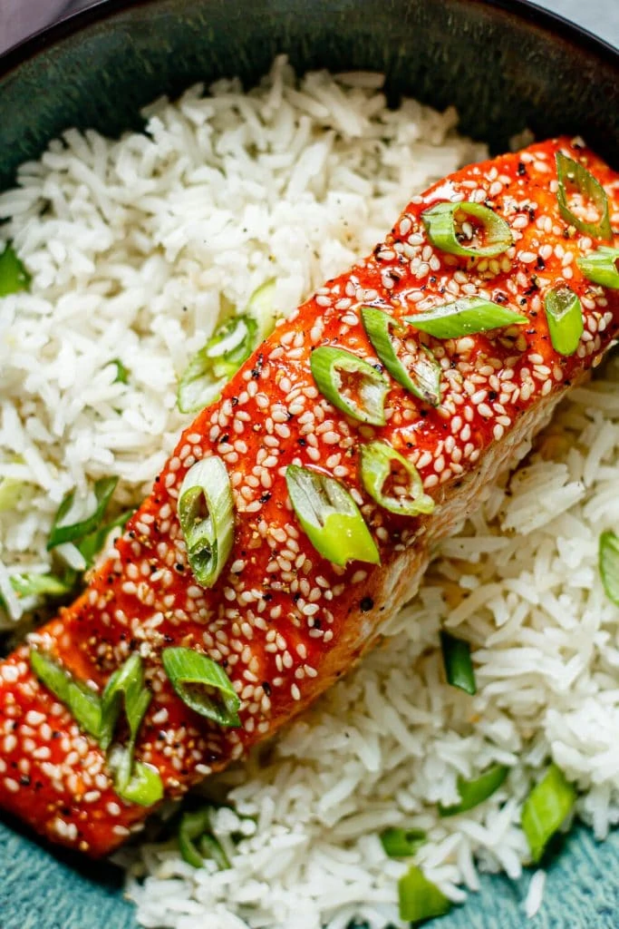 honey sriracha salmon over white rice with green onions on top