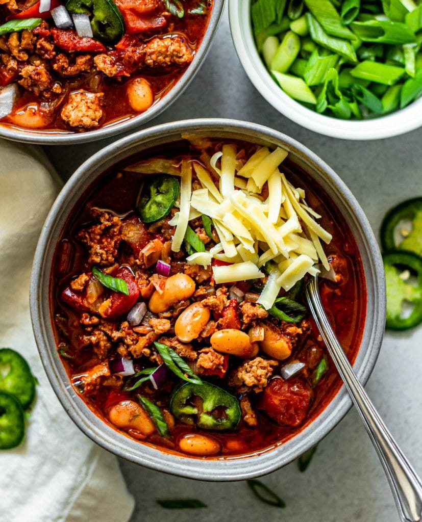 White bean turkey chili in a bowl topped with cheddar cheese