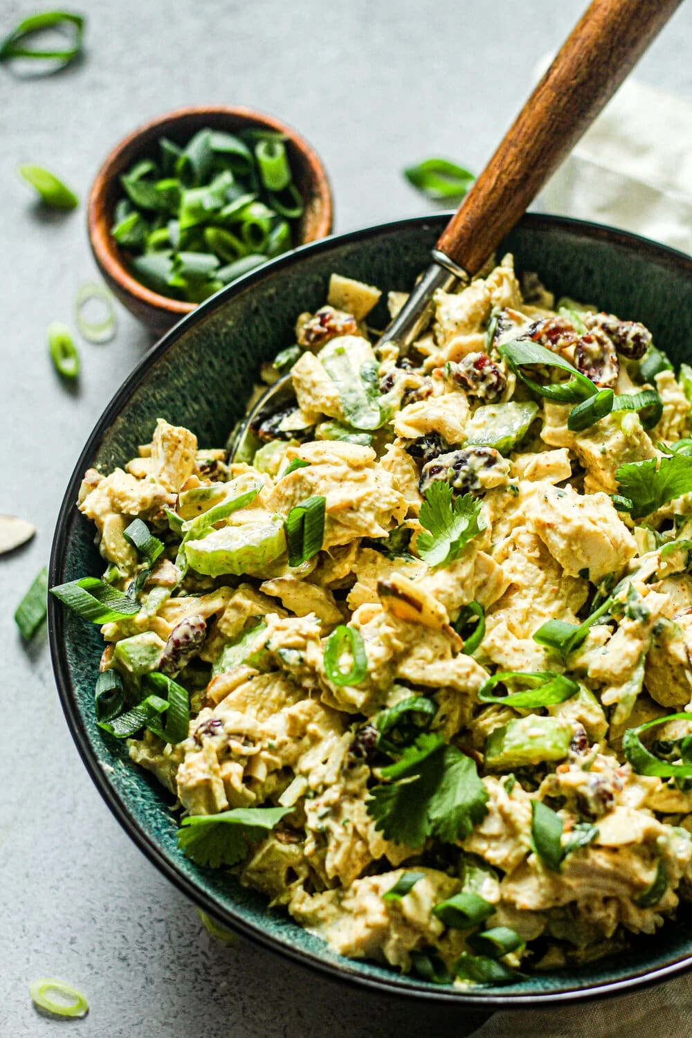 Curry Chicken Salad in a blue bowl with green onions in the background