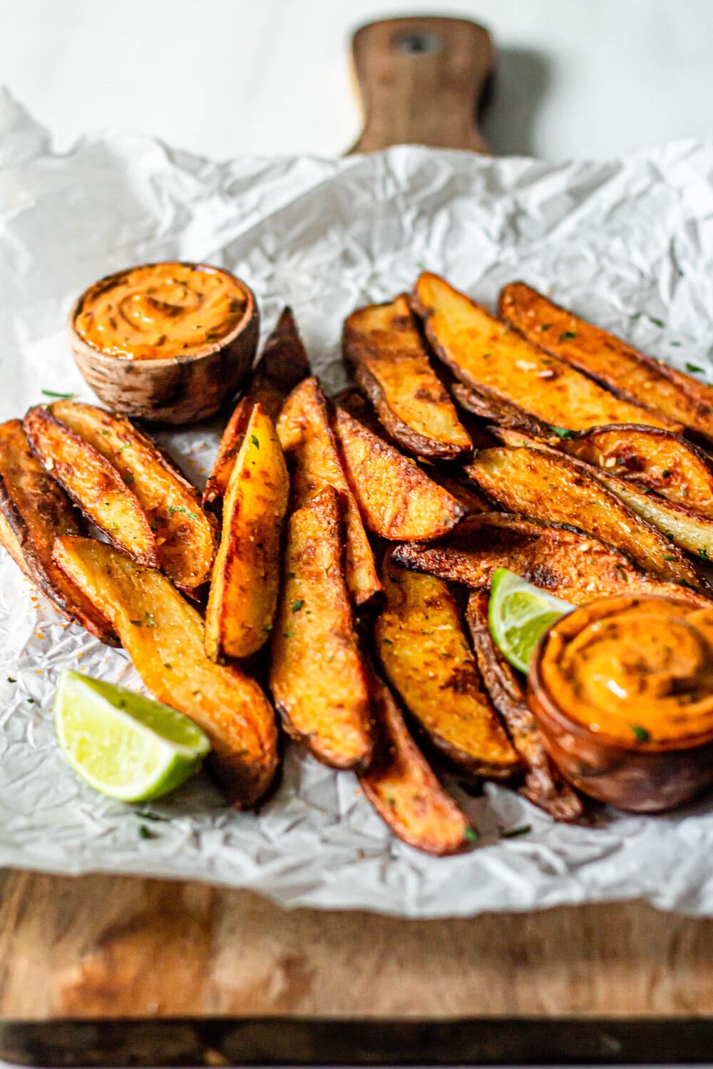 roasted potato wedges with chipotle lime aioli on white parchment paper