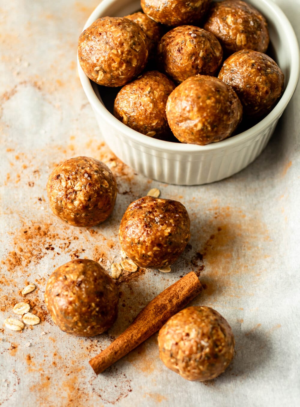 snickerdoodle energy bites in a white bowl with cinnamon stick on the side