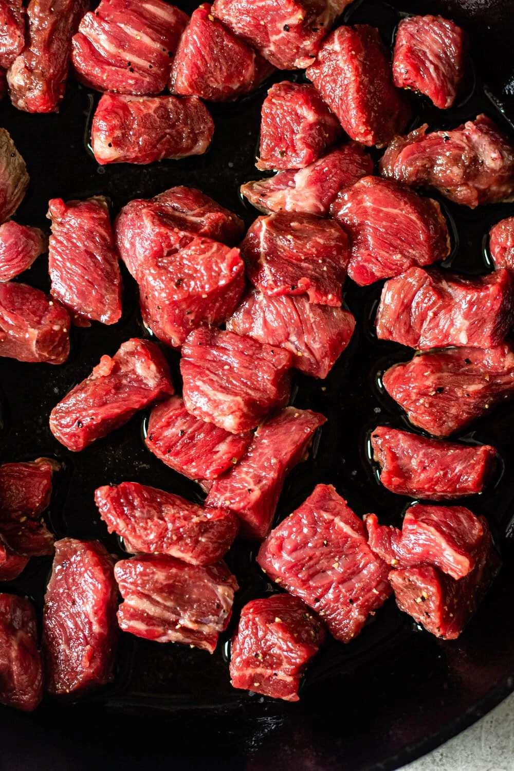 raw steak cooking in a cast iron skillet