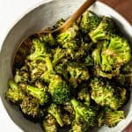 roasted garlic broccoli in a white bowl with gold spoon