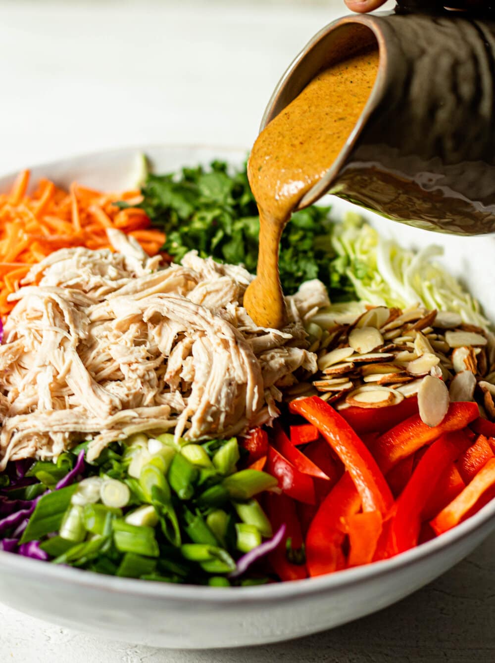 almond butter dressing poured over chopped thai chicken salad