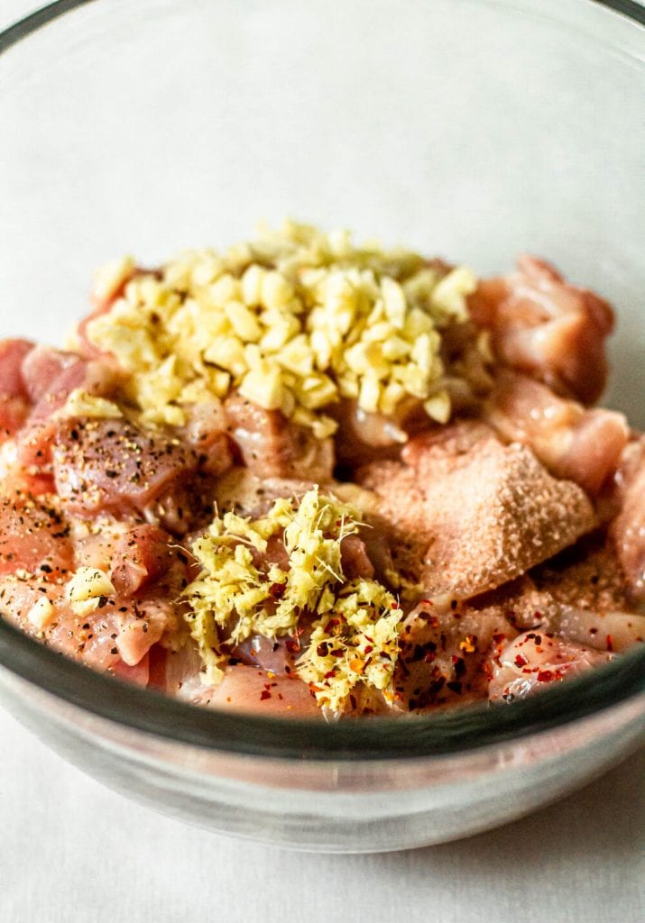 raw chicken with ginger garlic and salt in clear mixing bowl
