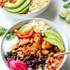 sheet pan chicken burrito bowl in white bowls with fork