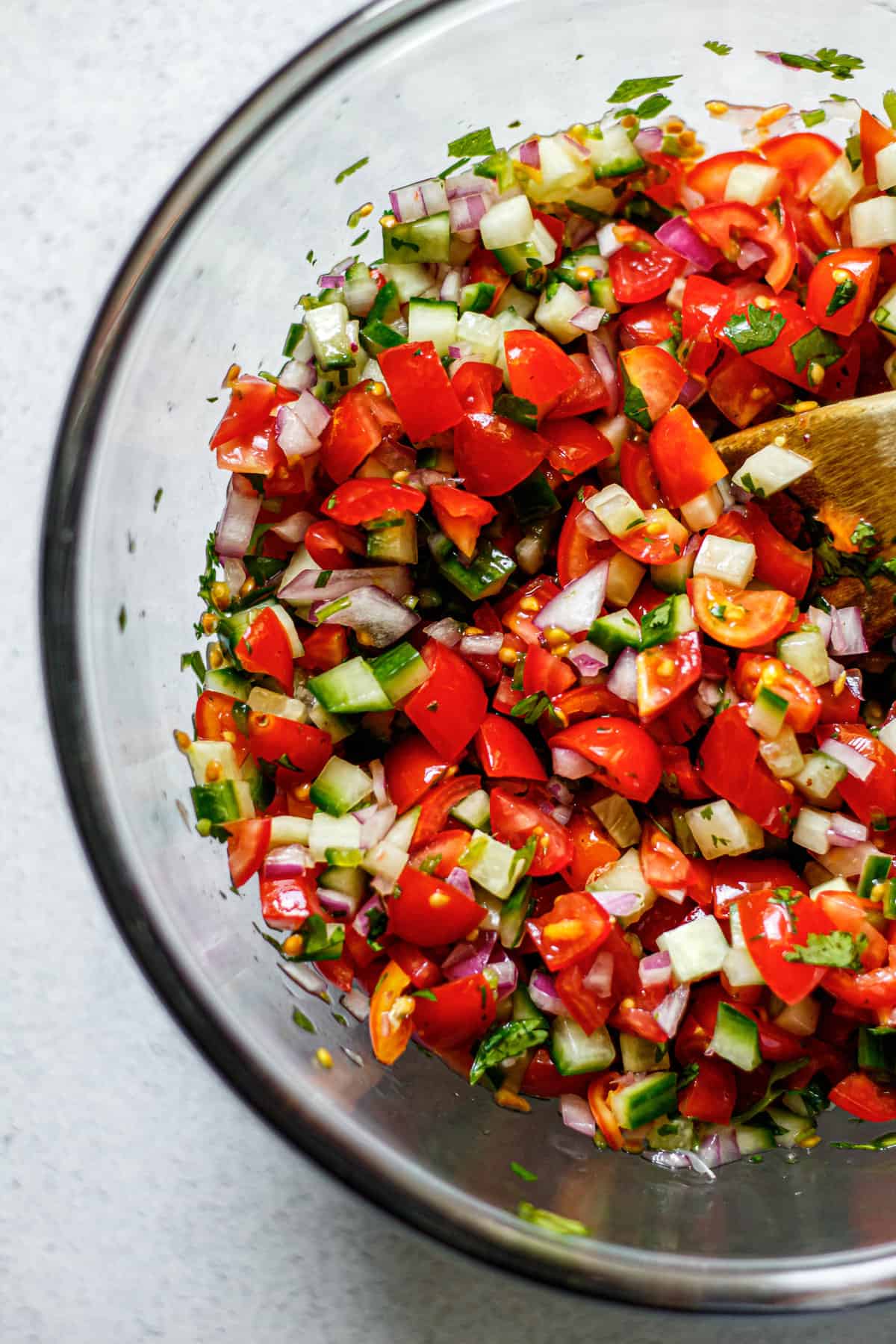 homemade Pico de Gallo in a clear bowl with a wooden spoon