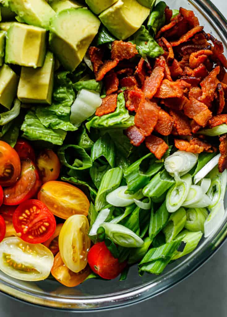  bacon, avocat, tomate, oignon vert et laitue romaine dans un bol à mélanger en verre 