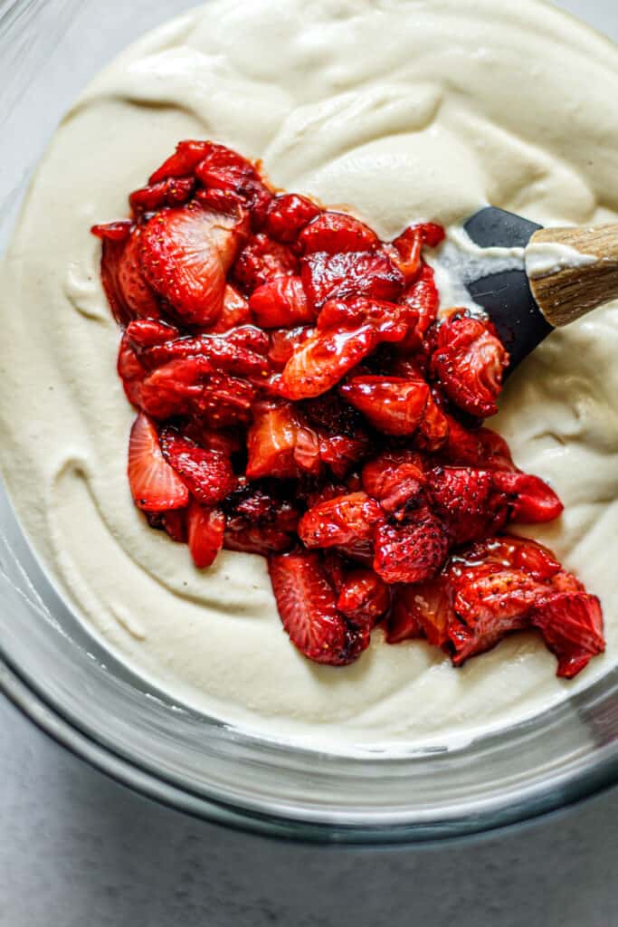 cheesecake filling in a clear bowl with roasted strawberries on top