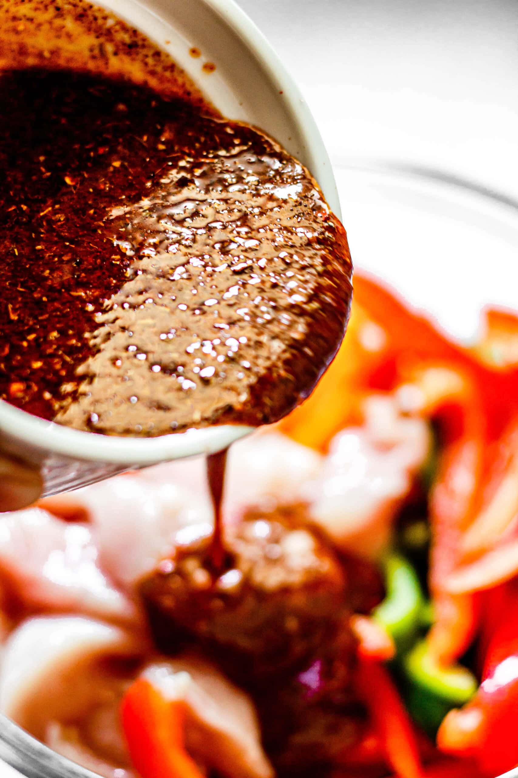marinade being poured over peppers and onions