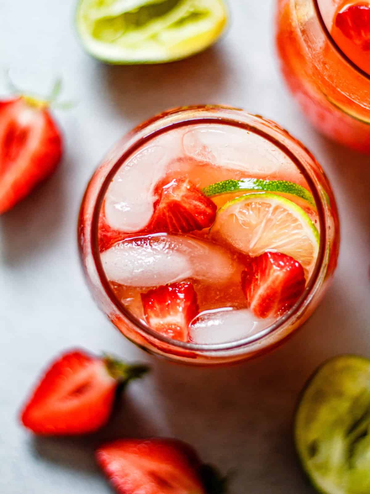sparkling strawberry limeade in a glass with lemons and limes around the glass