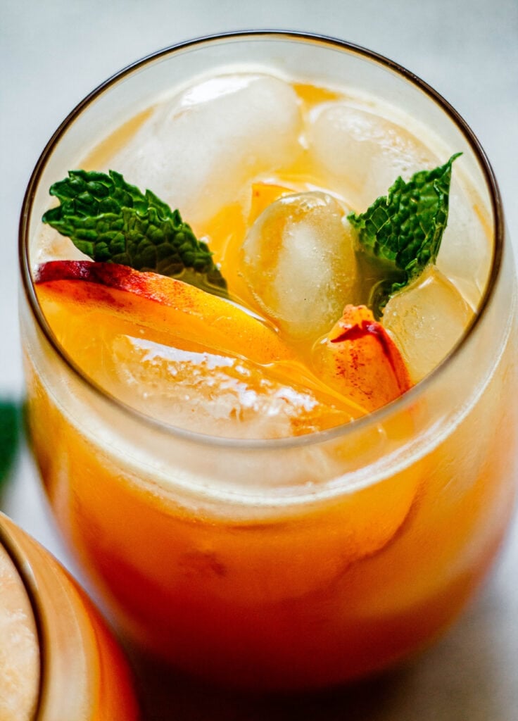 sparkling peach lemonade in a glass with fresh mint and sliced peaches