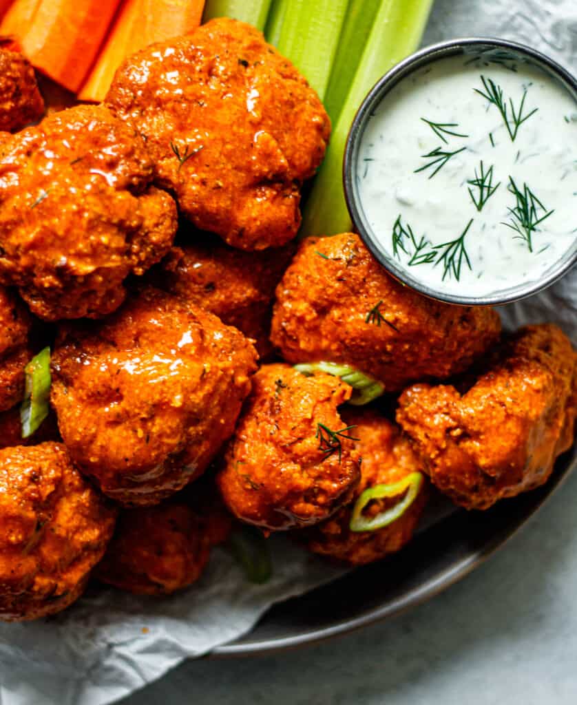 air fryer buffalo cauliflower on a plate with ranch dip, celery, and carrots