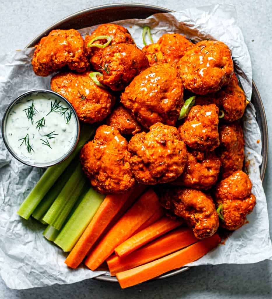air fryer buffalo cauliflower on a plate with celery, carrots, and ranch dip