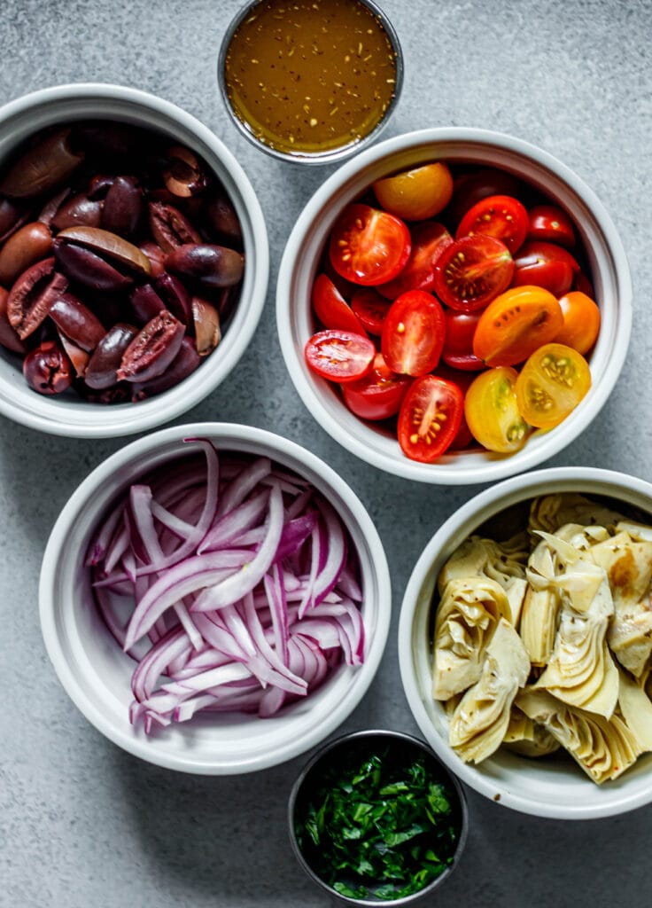 kalamata olives, red onion, tomatoes, artichoke hearts, parsley, and Greek dressing in small bowls