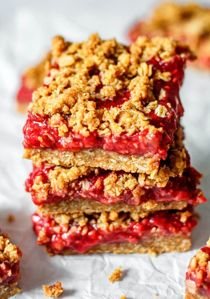 healthy raspberry oatmeal crumb bars stacked on top of each other