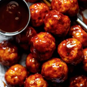 bbq chicken meatballs on a plate lined with parchment paper and a fork