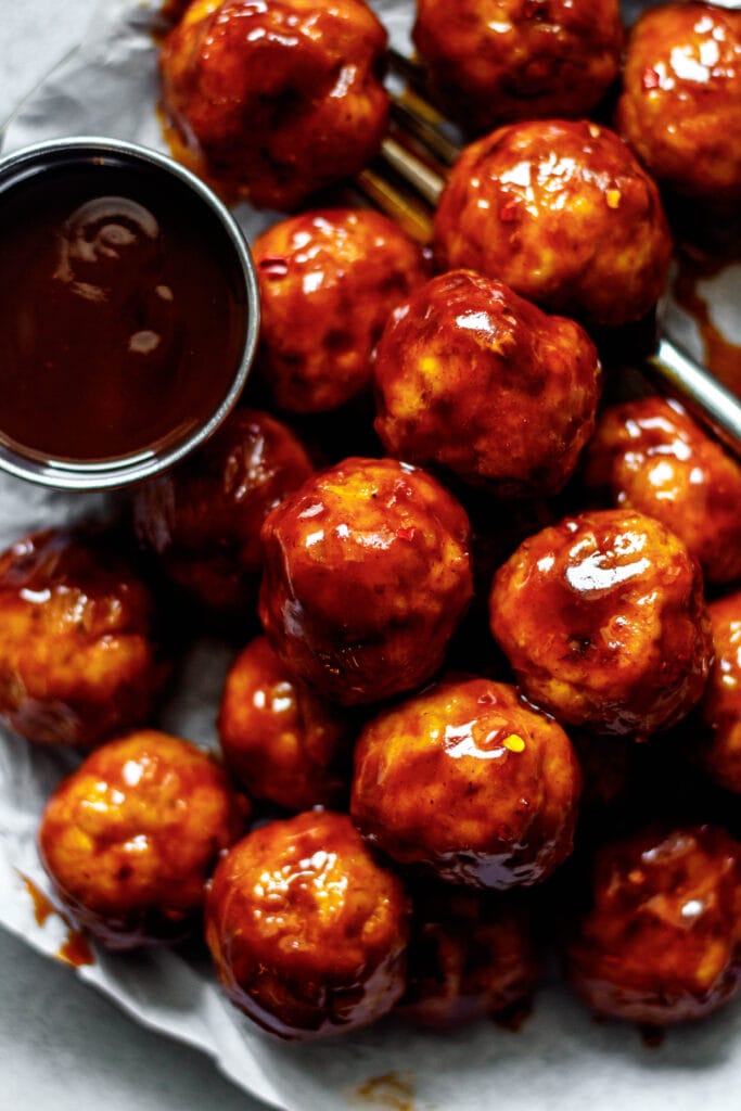 bbq chicken meatballs on a plate lined with parchment paper and a fork 