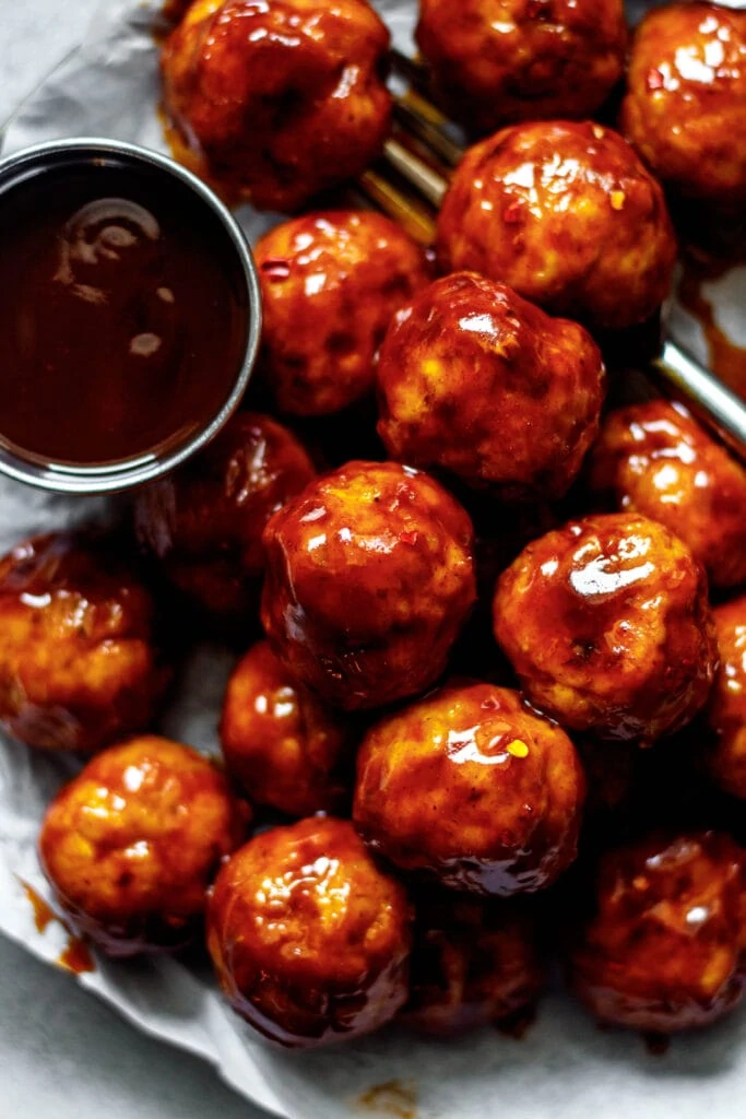 bbq chicken meatballs on a plate lined with parchment paper and a fork