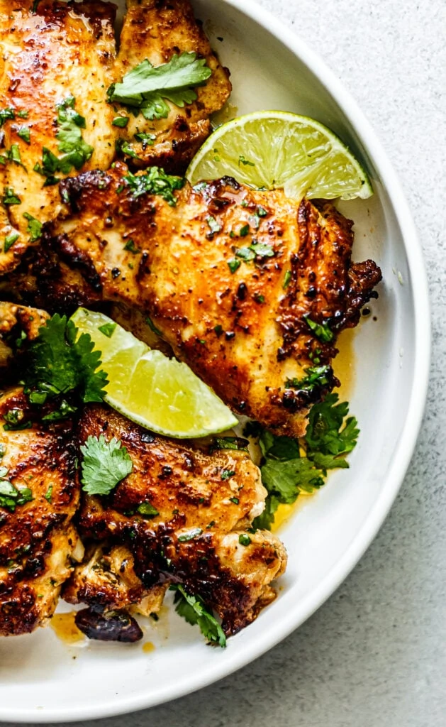 chicken thighs on white plate with lime