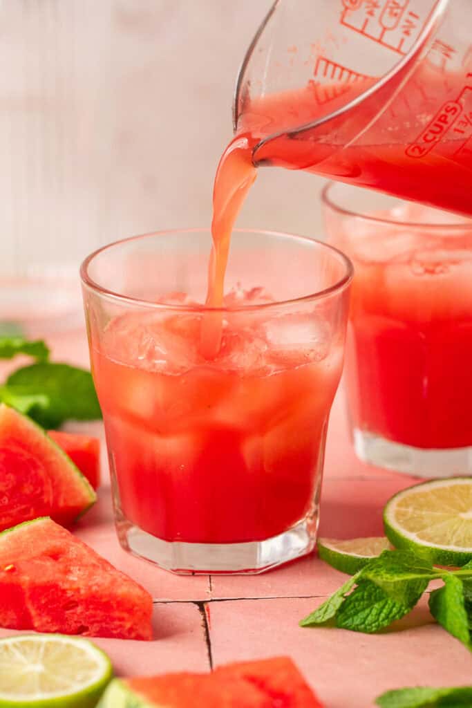 watermelon mocktail being poured over ice in glass
