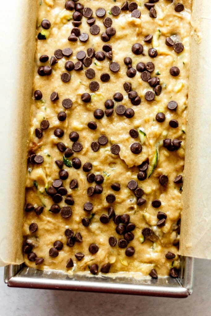 zucchini banana bread batter in a loaf pan lined with parchment paper