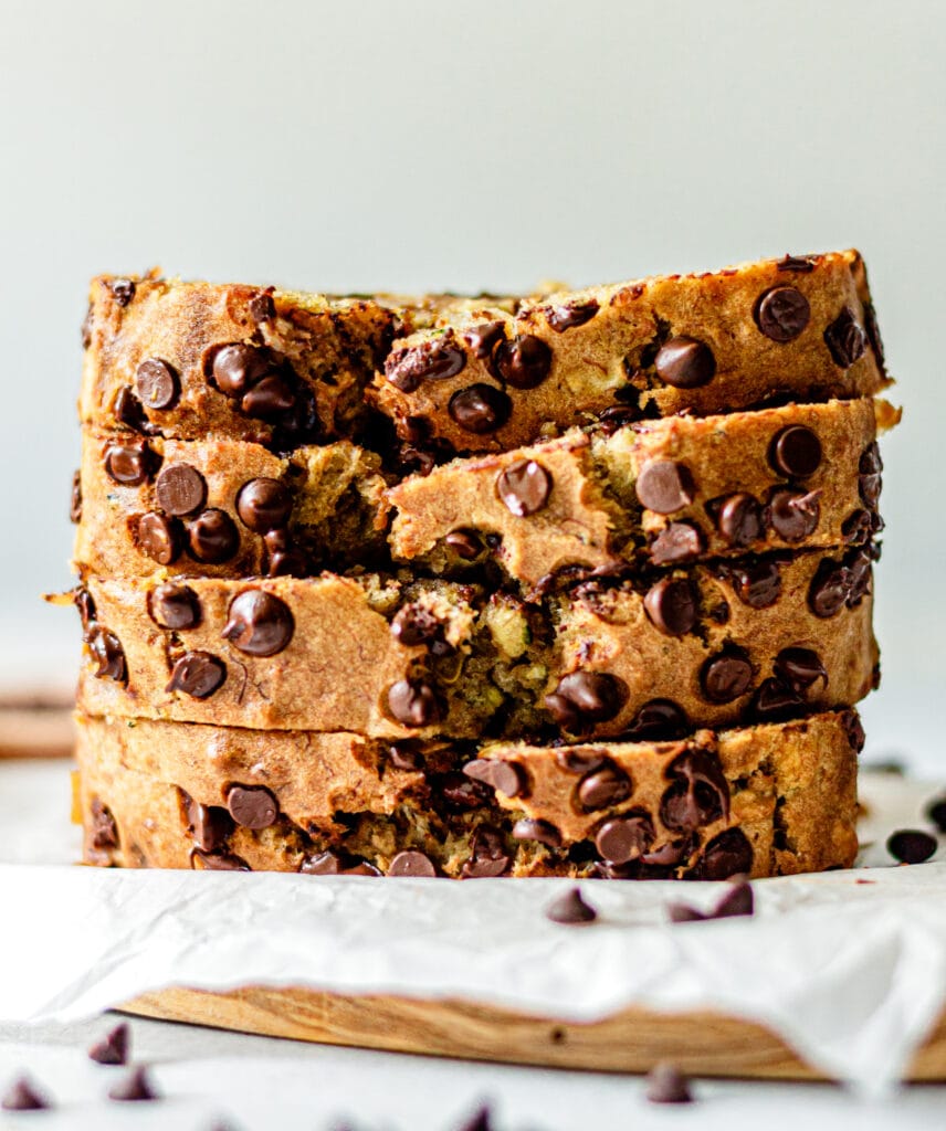 slices of banana bread stacked on top of each other on a brown cutting board lined with parchment paper