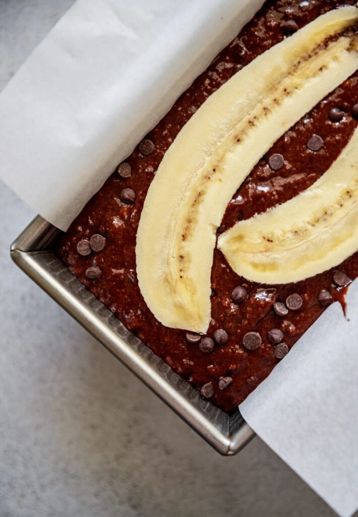 batter in a loaf pan topped with a banana