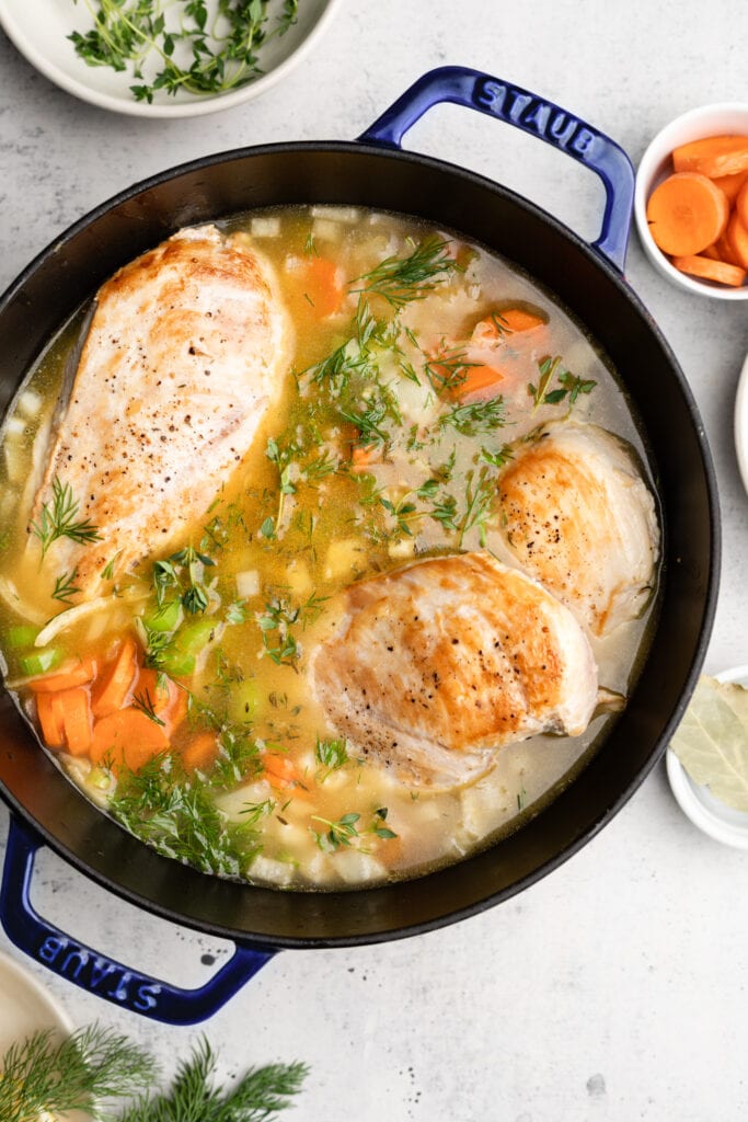 chicken soup in pot with three breasts