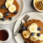 banana oatmeal pancakes on two plates with syrup