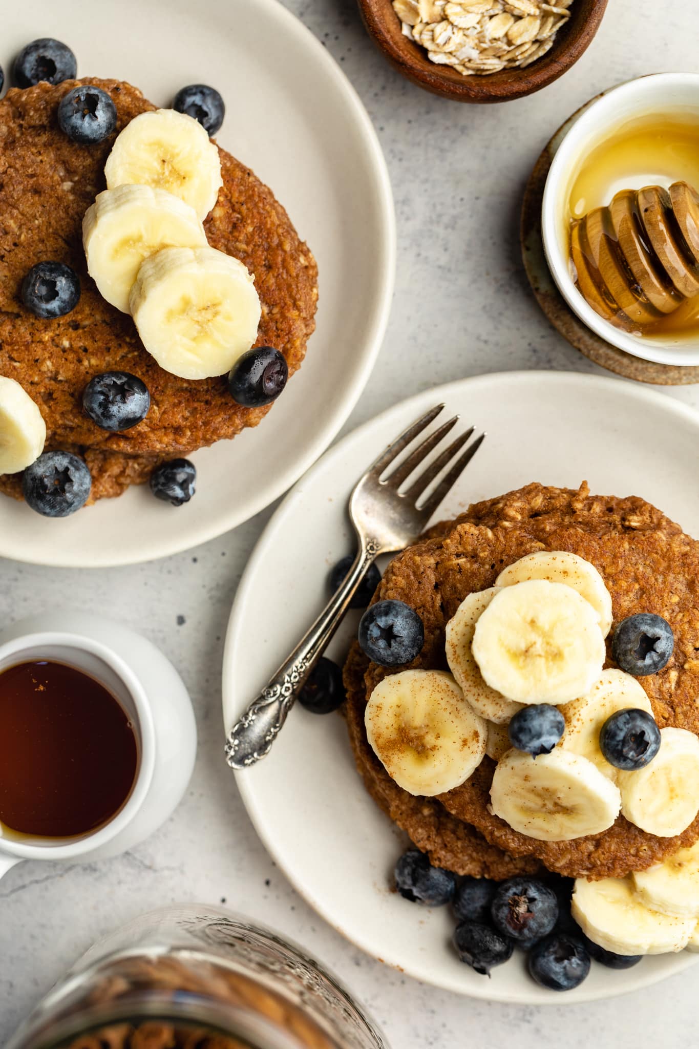 banana oatmeal pancakes on two plates with syrup
