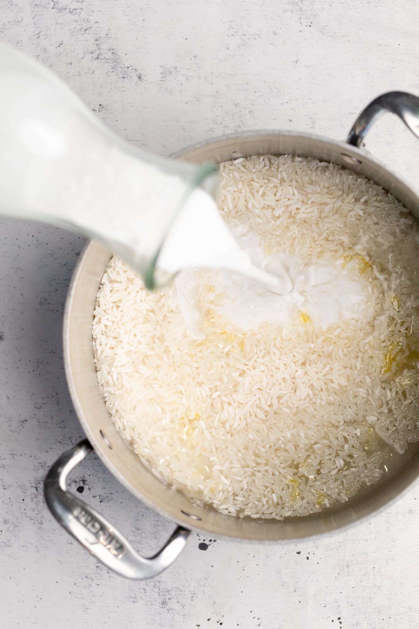 rice in pot with coconut oil being poured in