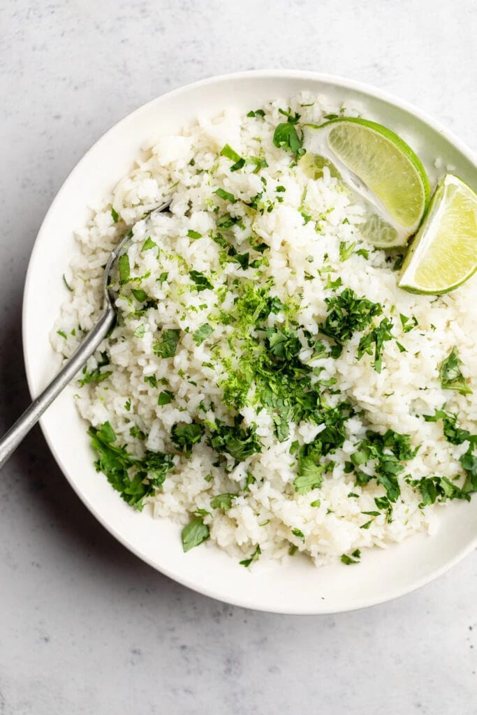 cilantro lime rice in bowl with limes and cilantro