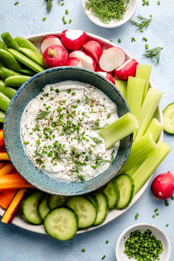 ranch dip in bowl with celery and plate of veggies