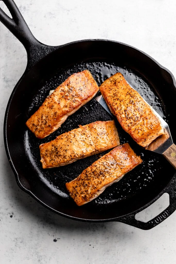 salmon cooking in cast iron skillet