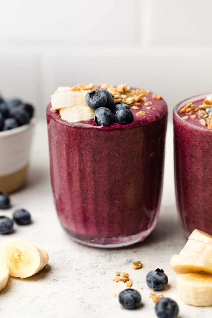blueberry banana smoothie in glass topped with fruit