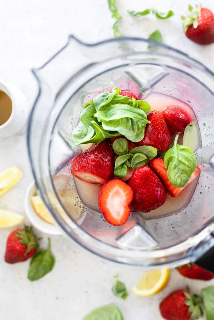 basil and strawberries in a blender
