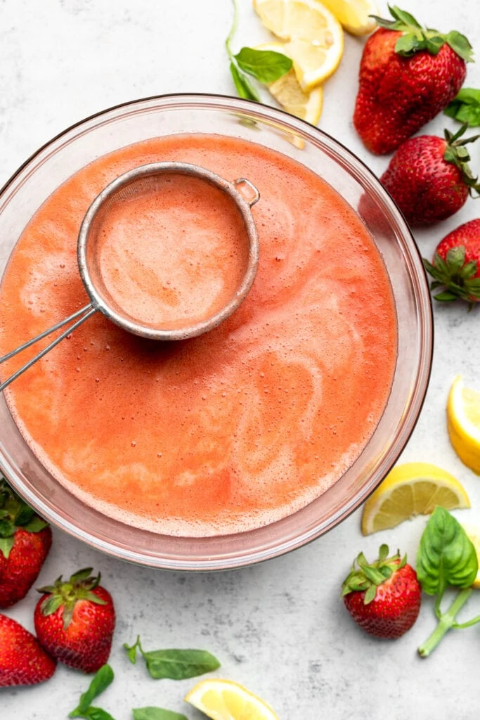 straining the strawberry lemonade in bowl