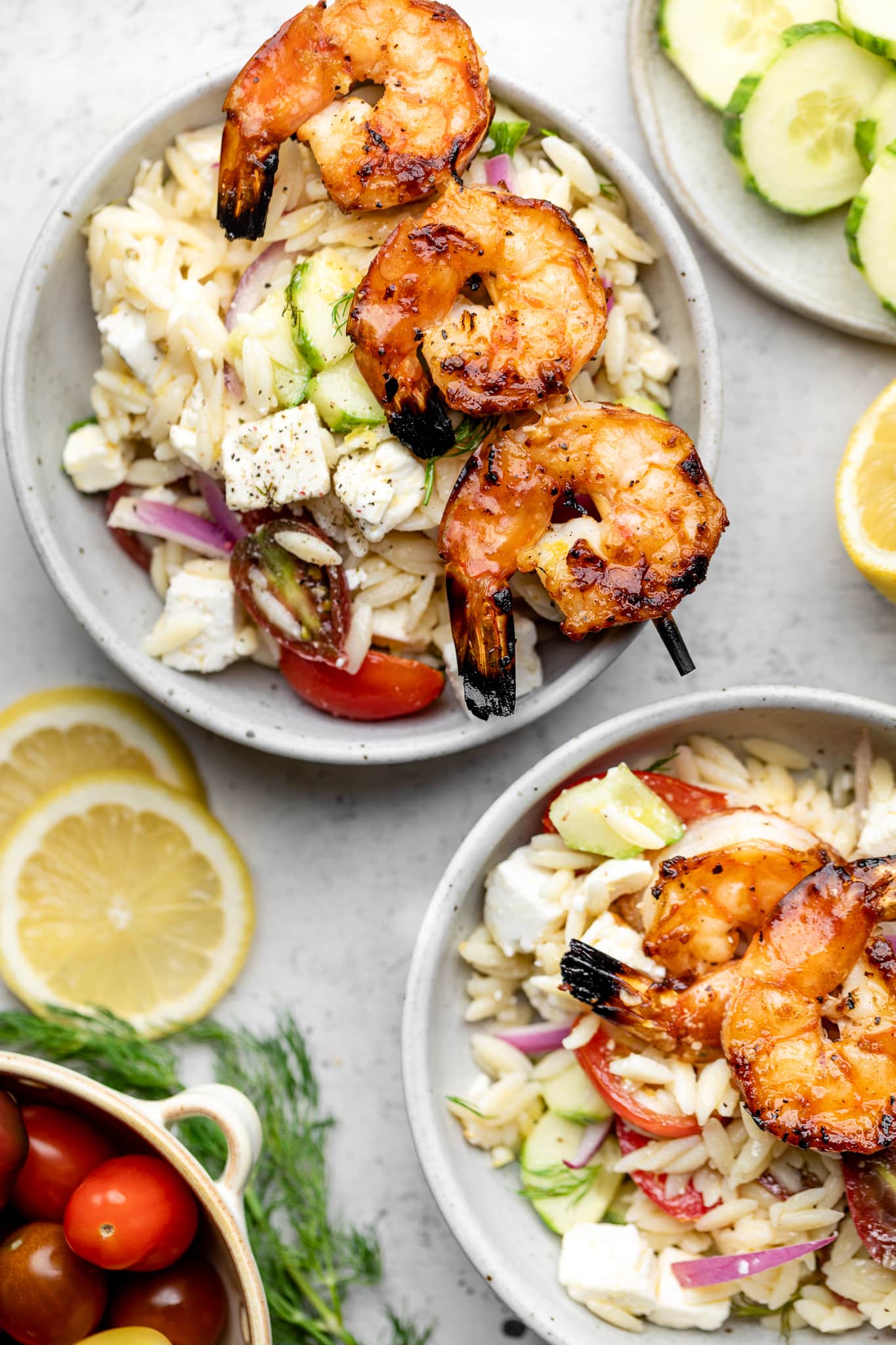 grilled shrimp skewers on top of orzo salad